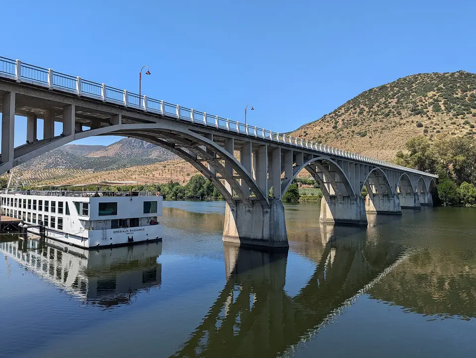 Die Bogenbrücke von Barca d'Alva über den Douro mit einem Kreuzfahrtschiff am Kai