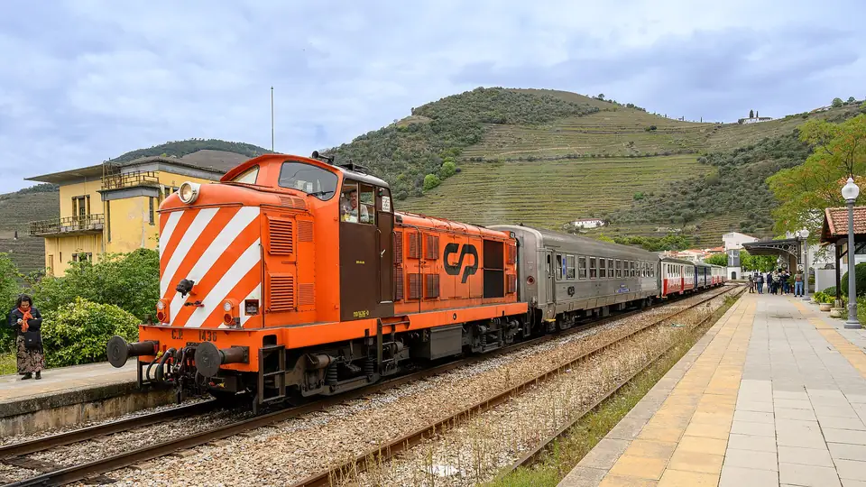 Eine orange CP-Lok mit dem Zug nach Pocinho am Bahnhof Pinhão